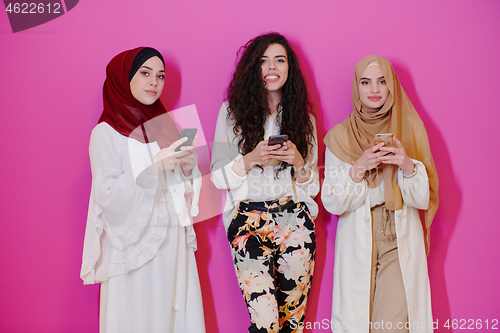 Image of muslim women using mobile phone isolated on pink