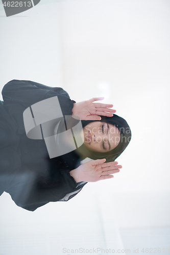 Image of young arabian muslim woman praying on the glass floor at home