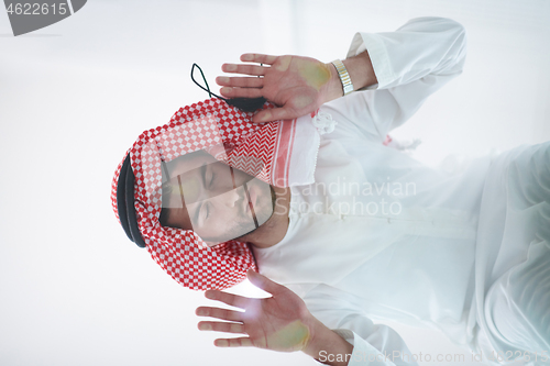 Image of young arabian muslim man praying on the glass floor at home
