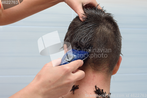 Image of Hairdresser cut half the hair on the back of the head of a man at home