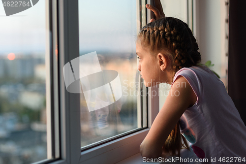 Image of Girl bored at home in quarantine looks out the window