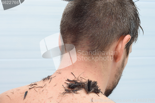 Image of The back of the head of a man whose hair is cut at home in the bathroom