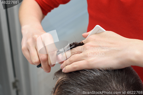 Image of Hairdresser smooths hairstyle for client, working at home