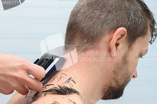 Image of Hairdresser shaves hairs from the neck of a man