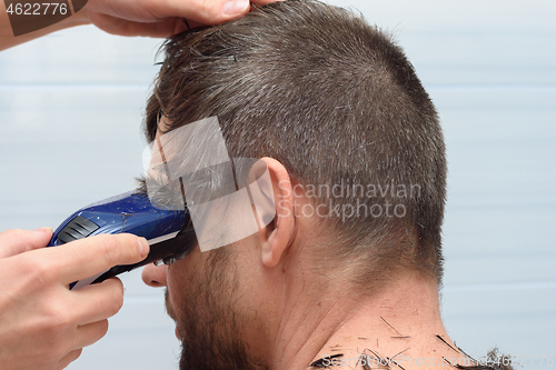 Image of The hairdresser cuts the hair on the head of a man, close-up