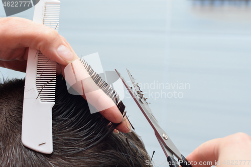 Image of Hairdresser straightens hair on the head with scissors and comb