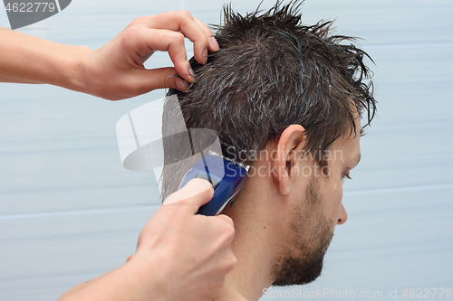 Image of The hairdresser begins to cut the hair on the mans head at home