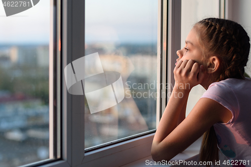 Image of The girl in self-isolation looks out the window