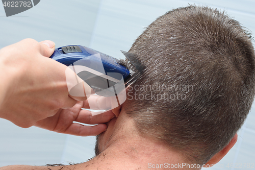 Image of Hairdresser smoothes and shortens the hair on the man\'s head in the bathroom