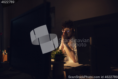 Image of Man working in office alone during coronavirus or COVID-19 quarantine, staying to late night