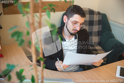 Image of Caucasian entrepreneur, businessman, manager working concentrated in office