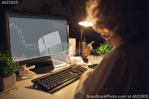 Image of Man working in office alone during coronavirus or COVID-19 quarantine, staying to late night