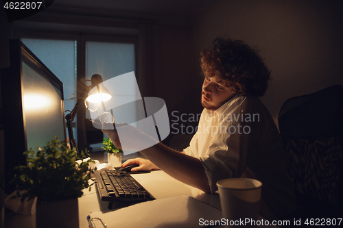 Image of Man working in office alone during coronavirus or COVID-19 quarantine, staying to late night