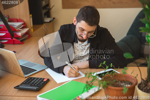 Image of Caucasian entrepreneur, businessman, manager working concentrated in office