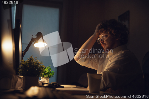 Image of Man working in office alone during coronavirus or COVID-19 quarantine, staying to late night