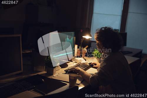 Image of Man working in office alone during coronavirus or COVID-19 quarantine, staying to late night