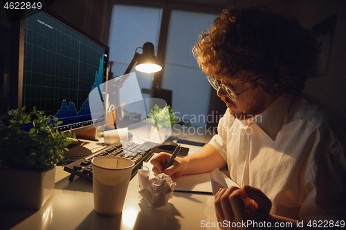 Image of Man working in office alone during coronavirus or COVID-19 quarantine, staying to late night