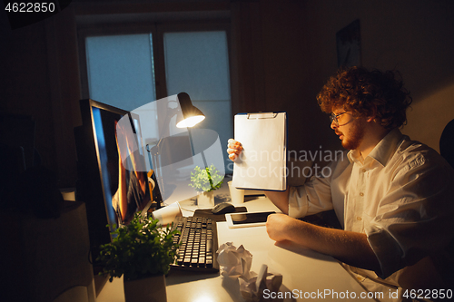 Image of Man working in office alone during coronavirus or COVID-19 quarantine, staying to late night