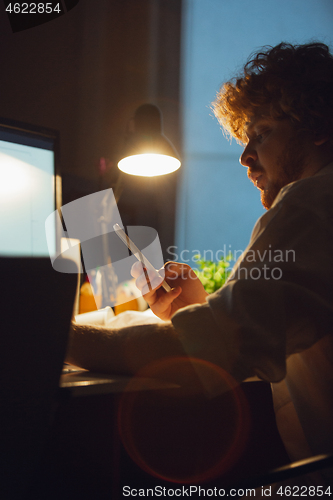 Image of Man working in office alone during coronavirus or COVID-19 quarantine, staying to late night