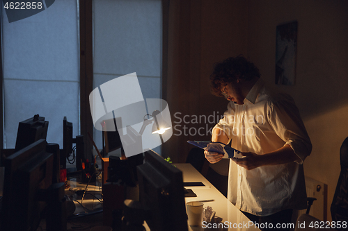 Image of Man working in office alone during coronavirus or COVID-19 quarantine, staying to late night