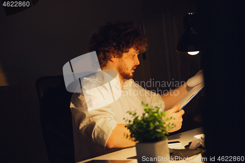 Image of Man working in office alone during coronavirus or COVID-19 quarantine, staying to late night