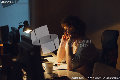 Image of Man working in office alone during coronavirus or COVID-19 quarantine, staying to late night