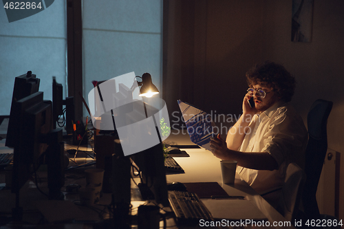 Image of Man working in office alone during coronavirus or COVID-19 quarantine, staying to late night