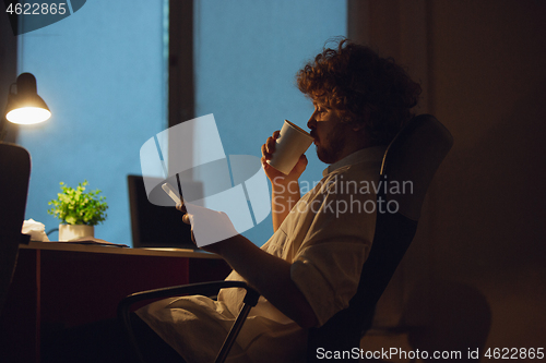 Image of Man working in office alone during coronavirus or COVID-19 quarantine, staying to late night