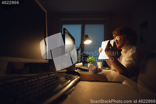 Image of Man working in office alone during coronavirus or COVID-19 quarantine, staying to late night