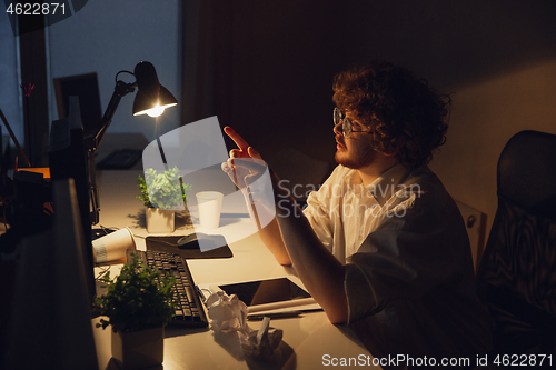 Image of Man working in office alone during coronavirus or COVID-19 quarantine, staying to late night