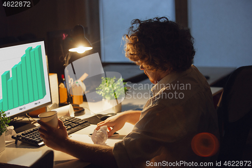 Image of Man working in office alone during coronavirus or COVID-19 quarantine, staying to late night