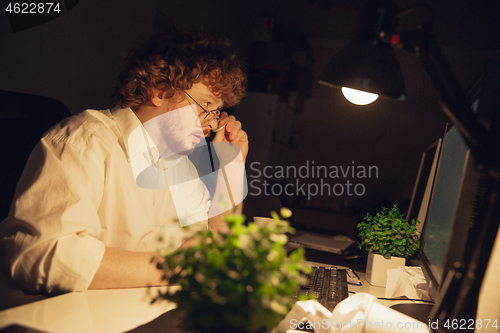 Image of Man working in office alone during coronavirus or COVID-19 quarantine, staying to late night