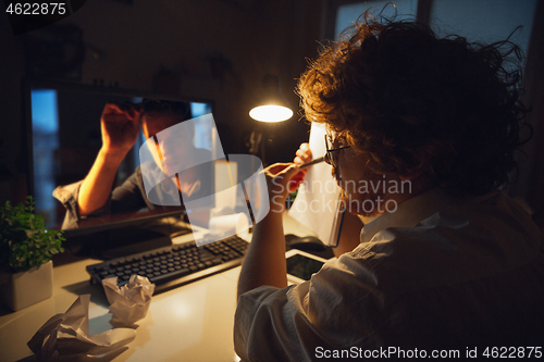 Image of Man working in office alone during coronavirus or COVID-19 quarantine, staying to late night