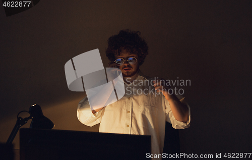 Image of Man working in office alone during coronavirus or COVID-19 quarantine, staying to late night