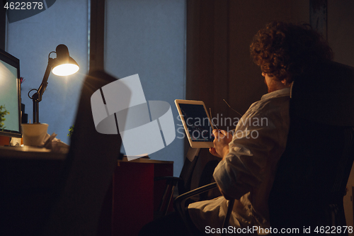 Image of Man working in office alone during coronavirus or COVID-19 quarantine, staying to late night