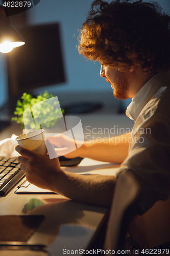 Image of Man working in office alone during coronavirus or COVID-19 quarantine, staying to late night