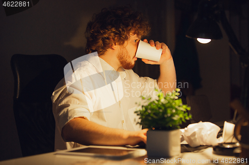 Image of Man working in office alone during coronavirus or COVID-19 quarantine, staying to late night