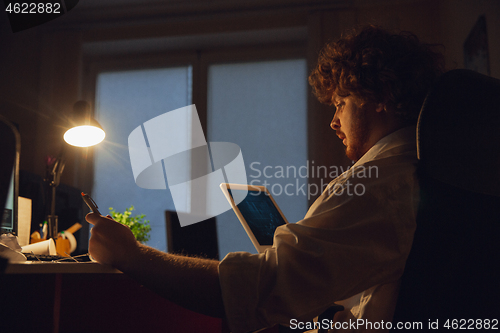 Image of Man working in office alone during coronavirus or COVID-19 quarantine, staying to late night