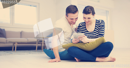 Image of Young Couple using digital tablet on the floor