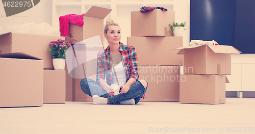 Image of woman with many cardboard boxes sitting on floor