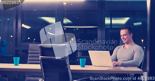 Image of man working on laptop in dark office