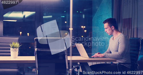 Image of man working on laptop in dark office