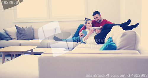 Image of couple relaxing at  home with tablet computers