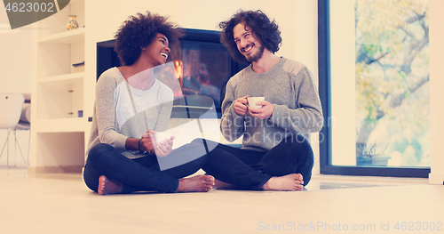 Image of multiethnic couple  in front of fireplace