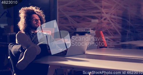 Image of businessman sitting with legs on desk at office