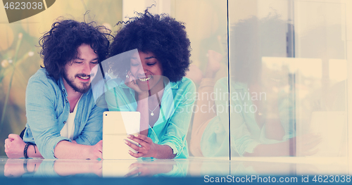 Image of Couple relaxing together at home with tablet computer