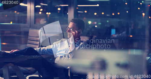 Image of businessman sitting with legs on desk at office