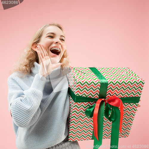 Image of Woman with big beautiful smile holding colorful gift box.