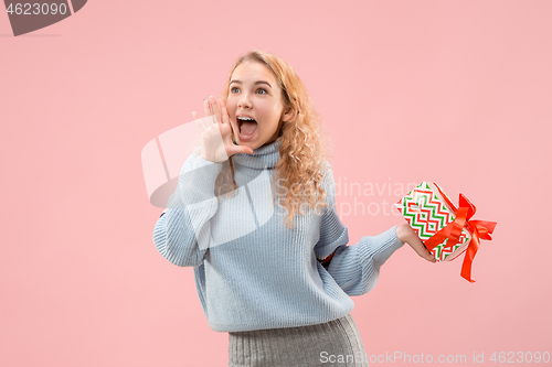 Image of Woman with big beautiful smile holding colorful gift box.