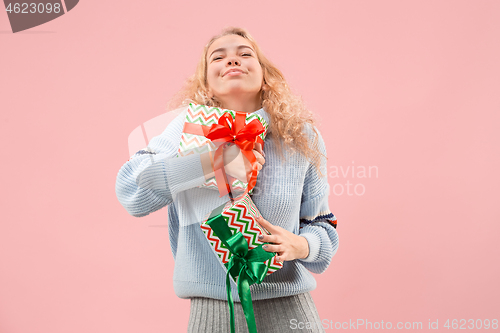 Image of Woman with big beautiful smile holding colorful gift boxes.